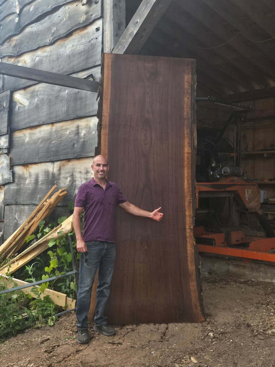 A sawyer standing beside a tall live edge slab at the mill